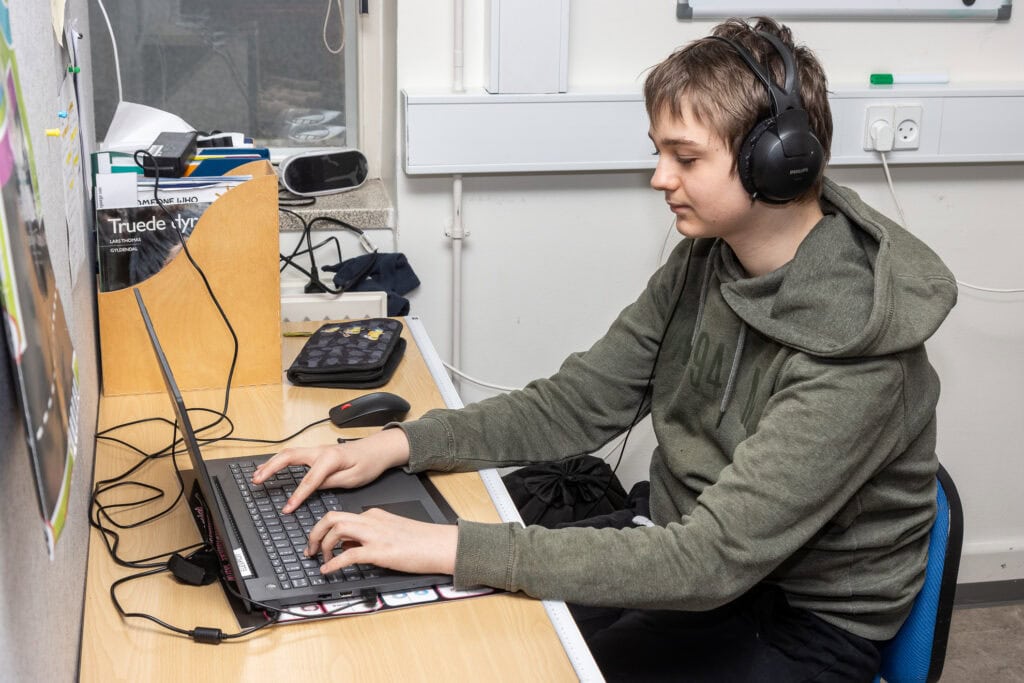 Foto med dreng ved computer og med høreværn ved Børneskolen, Filadelfia,